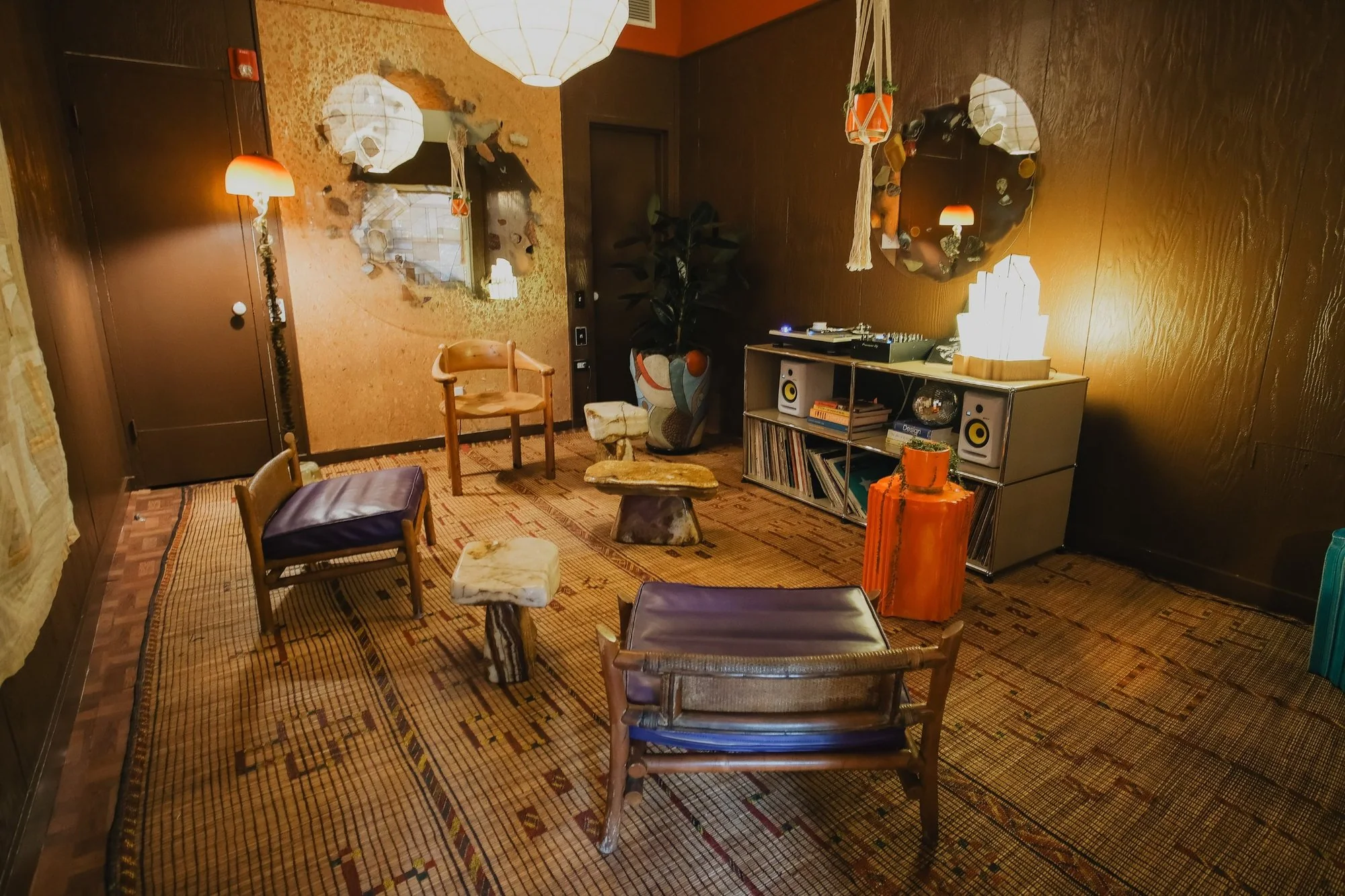 Wabi Sabi diorama: wood and leather chairs, stone stools, a woven rug and a record console under paper lanterns