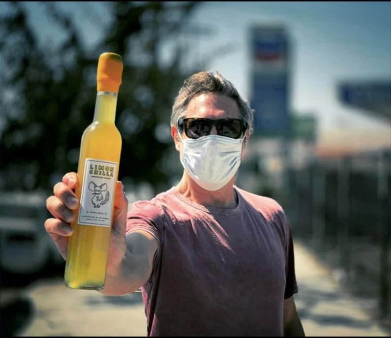 Peter, masked, holding up a bottle of Limonchilla